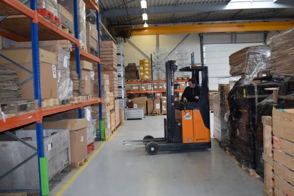 Reachtruck aan het werk tussen de magazijnstellingen